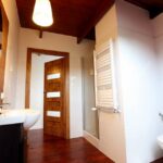 Nowoczesna łazienka w domku na Kaszubach z drewnianą podłogą i sufitem, toaletą, umywalką i lustrem