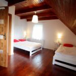 Przytulna sypialnia na poddaszu domku na Kaszubach z drewnianymi belkami, dwoma łóżkami i oknem