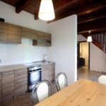 Nowoczesna kuchnia w domku na Kaszubach z drewnianymi szafkami, stołem jadalnym i widokiem na schody