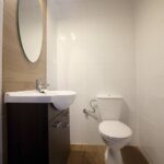 Czysta łazienka w domku na Kaszubach z toaletą, umywalką na szafce i owalnym lustrem